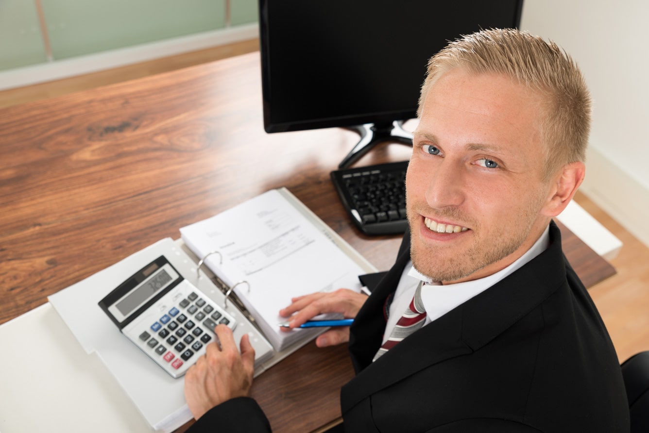 happy-businessman-calculating-finance-in-office